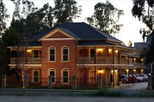 a brick house with a balcony on a street at Carlyle Suites & Apartments in Wagga Wagga