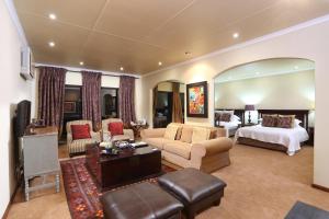 um grande quarto de hotel com uma cama e uma sala de estar em Shangri-La Manor em Hoekwil
