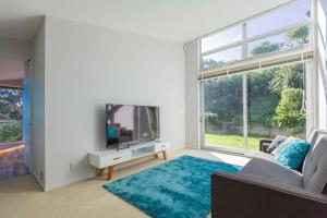 a living room with a tv and a large window at Exclusive Sanctuary on the West Coast in Muriwai Beach