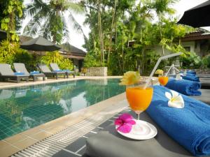 a drink on a table next to a swimming pool at Bangtao Beach Chalet Resort in Bang Tao Beach
