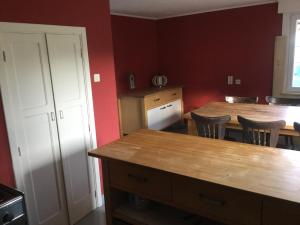 a kitchen with two tables and chairs and red walls at Gîte de la Fourîre in Stoumont