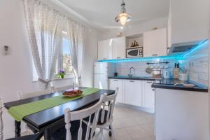 a kitchen with white cabinets and a black counter top at SeaView Apartment Toni in Milna