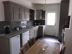 a kitchen with white cabinets and a wooden table at Glens of Antrim Beach House - On the Coast in Glenariff