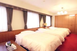a hotel room with three beds and a table at Kagoshima Kuko Hotel in Kirishima