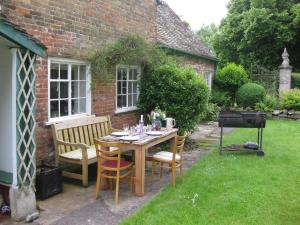 una mesa de madera y sillas en un jardín en Job's Mill Cottage en Warminster