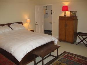 a bedroom with a bed and a dresser and a red lamp at Job's Mill Cottage in Warminster