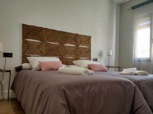 une chambre avec un grand lit avec des oreillers roses et blancs dans l'établissement VIVIENDA ÚBEDA REAL, à Úbeda
