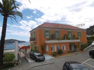 a building with a car parked in a parking lot at Hôtel La Flore in Villefranche-sur-Mer