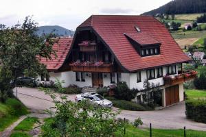 a house with a red roof and a car parked in front at Martina Frey Ferienwohnungen in Baiersbronn +21 photos