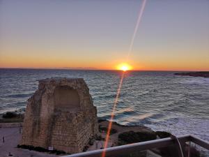 einen Sonnenuntergang über dem Meer mit einer Steinstruktur in der Unterkunft Hotel Belvedere in Torre dell'Orso