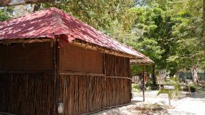 a small wooden building with a red roof at Soul Breeze Backpackers Diani in Diani Beach