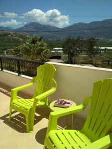 two green chairs and a table on a balcony at Villa Doxa in Ierápetra
