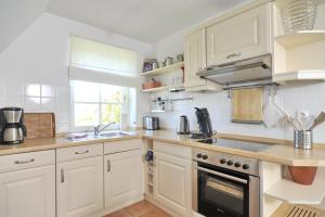 una cocina con armarios blancos y fregadero en Appartement Nordseesonne, en Wenningstedt