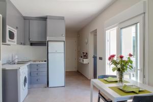 una cocina con electrodomésticos blancos y una mesa con un jarrón de flores en Canyamel 27, en Canyamel