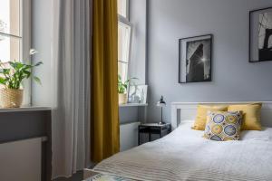 - une chambre avec un lit et une fenêtre avec des rideaux jaunes dans l'établissement Apartament Jana Matejki, à Poznań