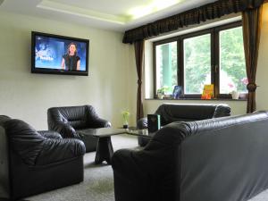 a living room with two leather chairs and a tv at Waldhotel Wandlitz in Wandlitz