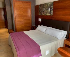 a bedroom with a bed with a purple blanket on it at Hotel Balneario Valle del Jerte in Valdastillas