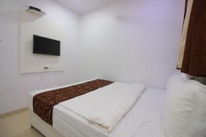 a bedroom with a bed and a tv on a wall at Hotel Apex in Navi Mumbai