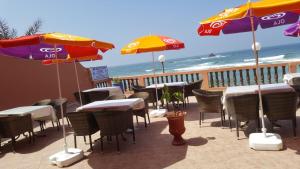 a patio with tables and chairs and umbrellas on the beach at HOTEL BEACH CLUB LEGZIRA in Sidi Ifni