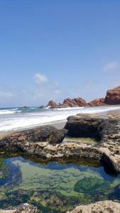 a beach with rocks and water and the ocean at HOTEL BEACH CLUB LEGZIRA in Sidi Ifni