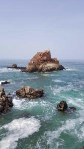 a group of rocks in the ocean with waves at HOTEL BEACH CLUB LEGZIRA in Sidi Ifni