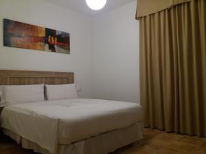 a bedroom with a white bed and a curtain at La casa del viajero in Ardales +26 photos