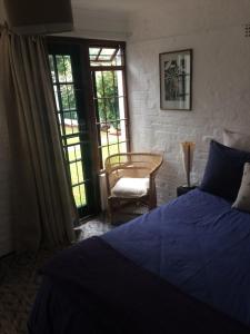 a bedroom with a blue bed and a chair at Delightful Surrey Street in Cape Town