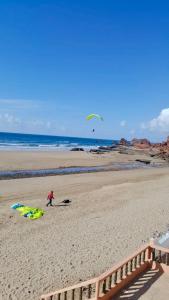 a person is flying a kite on a beach at HOTEL BEACH CLUB LEGZIRA in Sidi Ifni