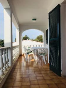 a room with a table and chairs on a balcony at Casa 3 dormitorios Cala Galdana in Cala Galdana