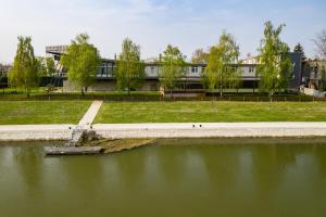 a body of water with a building in the background at Amstel Hattyú Panzió -Érintésmentes bejelentkezés in Győr