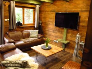 een woonkamer met lederen meubels en een flatscreen-tv bij Chalet Račkova dolina in Pribylina