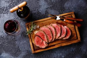 a cutting board with slices of meat and a glass of wine at Kings Arms Hotel in Melrose