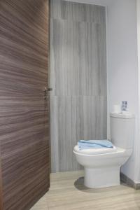 a bathroom with a toilet and a wooden door at Fedrania Gardens Hotel in Ayia Napa