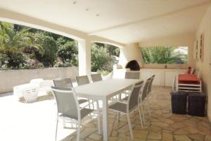 une table blanche et des chaises sur une terrasse dans l'établissement Les Myrtes, aux Issambres