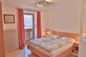 Schlafzimmer mit einem Bett mit roten Vorhängen und einem Fenster in der Unterkunft Appartements Wiesenheim in Oberrasen