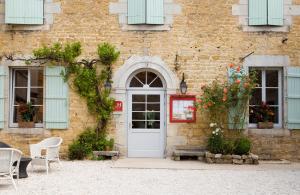 een bakstenen gebouw met een witte deur en ramen bij Hotel-restaurant Les Caudalies in Arbois