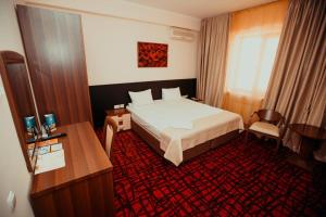 um quarto de hotel com uma cama e uma secretária em Alma em Almaty