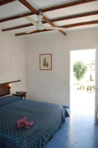 a bedroom with a bed with purple flowers on it at Hotel Conti in Vulcano