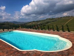 uma piscina num pátio de tijolos com uma colina em Villa Garassino em Treiso