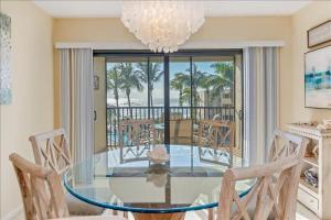 uma sala de jantar com uma mesa de vidro e um lustre em Sea Oats 336 Condo em Boca Grande