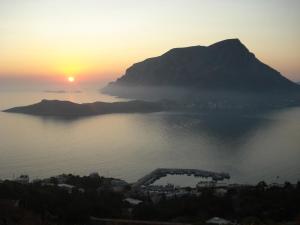 una puesta de sol sobre un cuerpo de agua con una montaña en Studios Aeolos Kalymnos, en Myrties