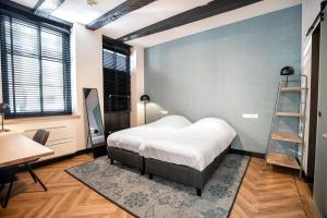 een slaapkamer met een bed, een bureau en een ladder bij Boutique hotel WKNDS in Leeuwarden
