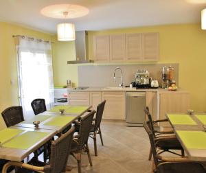 a kitchen with tables and chairs and a kitchen with yellow walls at Hôtel l'Anvia in Bollène