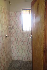 a bathroom with a shower with a window and a door at Gateway Guest House in Monkey Bay