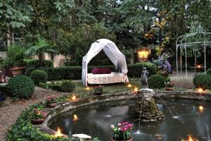 a bed in a tent in a garden with a pond at La Striscia Wine Resort in Arezzo