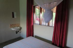a bedroom with a bed and a window with red curtains at Gateway Guest House in Monkey Bay