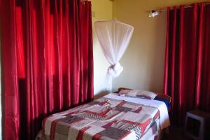 a bedroom with red curtains and a bed with a canopy at Gateway Guest House in Monkey Bay