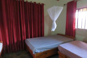 a bedroom with two beds and red curtains at Gateway Guest House in Monkey Bay