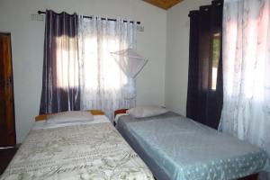 two beds in a room with curtains and a window at Gateway Guest House in Monkey Bay