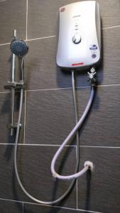 a shower head with a hose attached to a wall at AK Homestay in Port Dickson